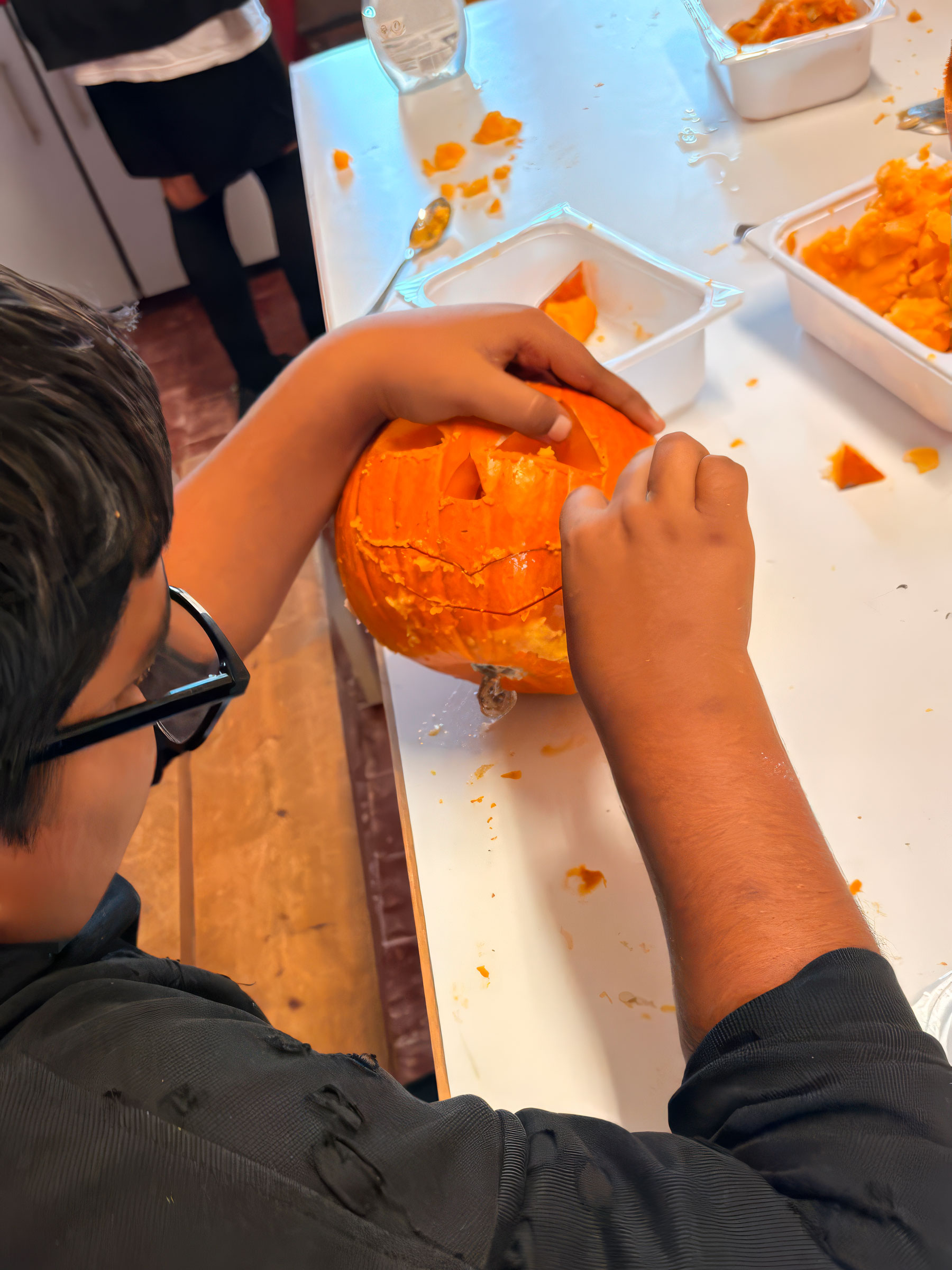 Un ragazzo del Centro Socio Educativo Tandem intaglia una zucca durante un laboratorio creativo.