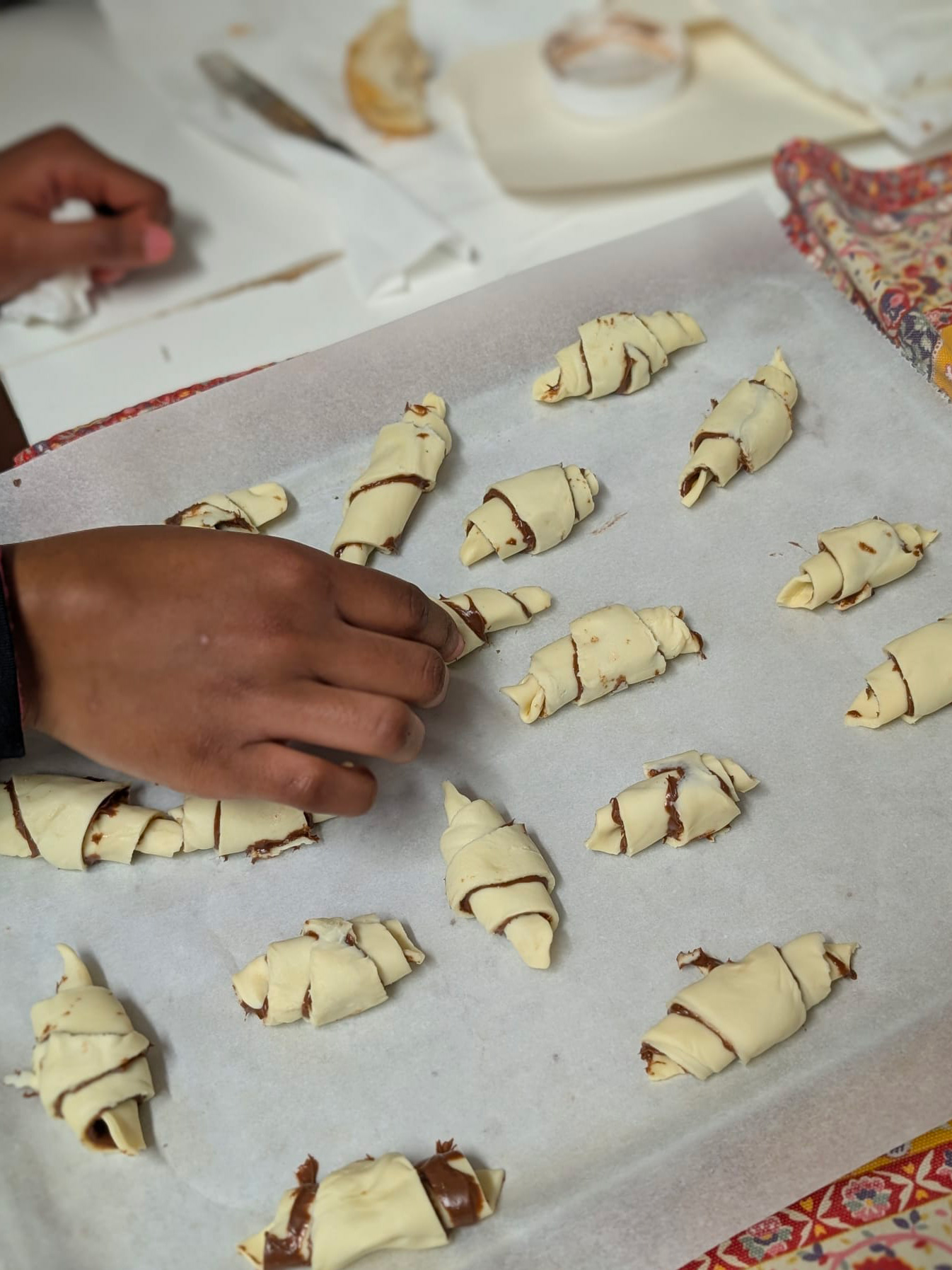Un ragazzo del Centro Socio Educativo Tandem prepara piccoli croissant durante un laboratorio di cucina.